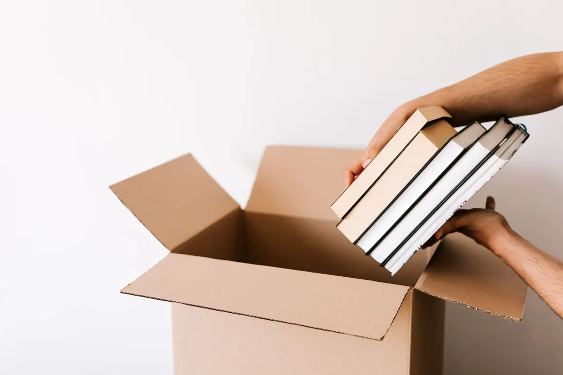 Bücher werden kurzfristig in einen Umzugskarton gepackt
