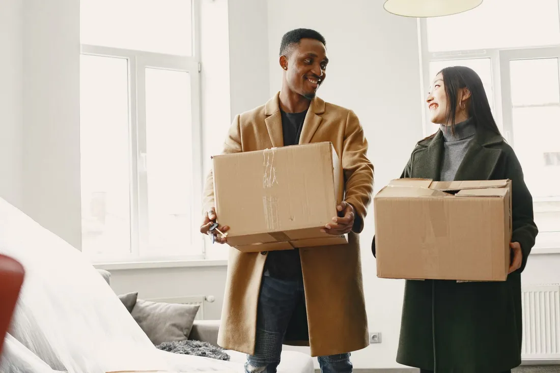 Paar trägt Umzugskartons in die neue Wohnung