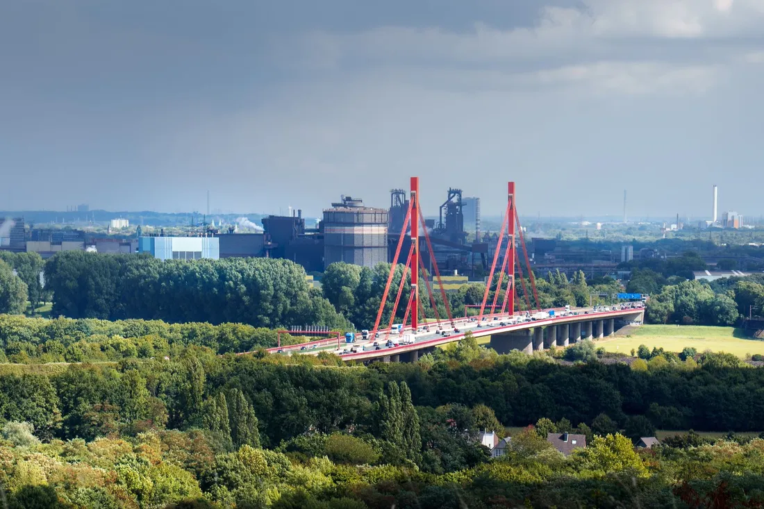 Autobahnbrücke mit Lastverkehr vor Industrieanlagen im Ruhrgebiet