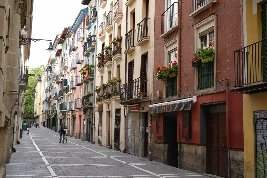 Schmale Altstadtgasse mit bunten Hausfassaden und Blumenkästen in Spanien