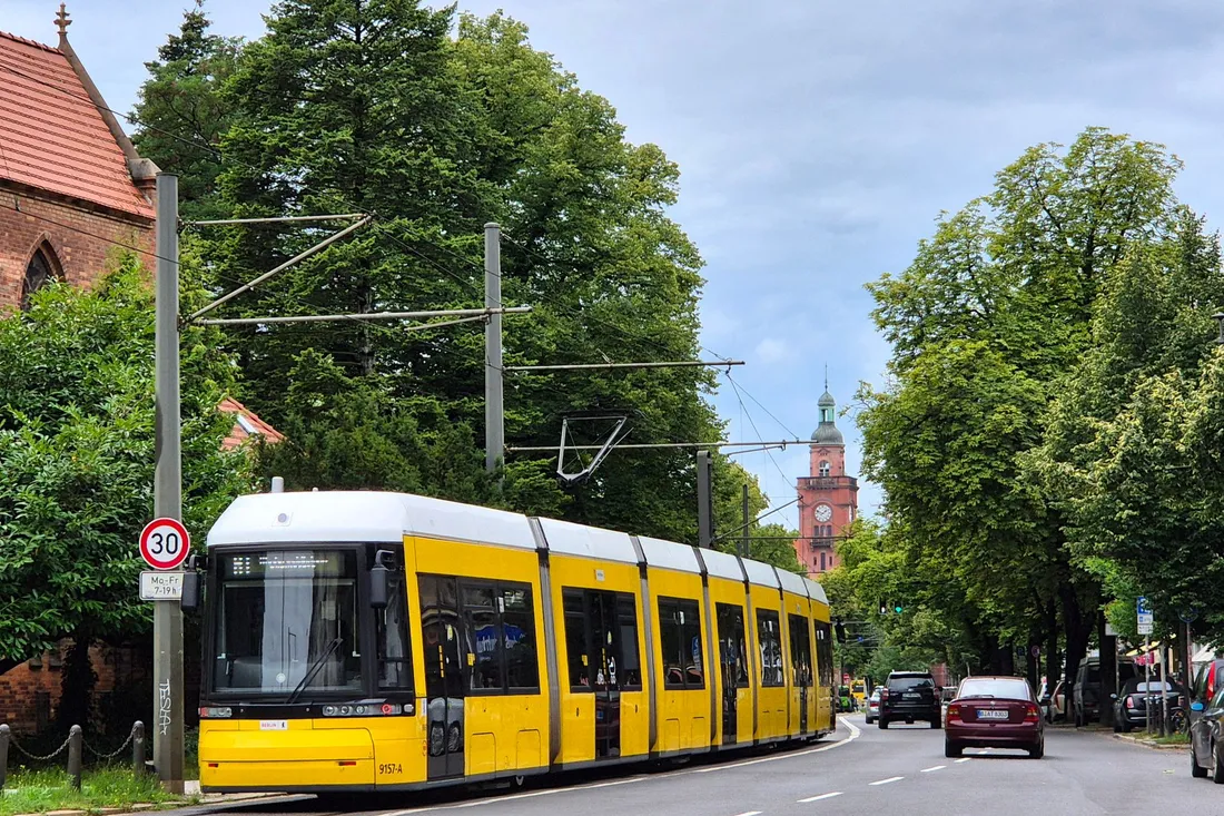 Gelbe Berliner Straßenbahn auf einer Hauptstraße mit Baumreihe