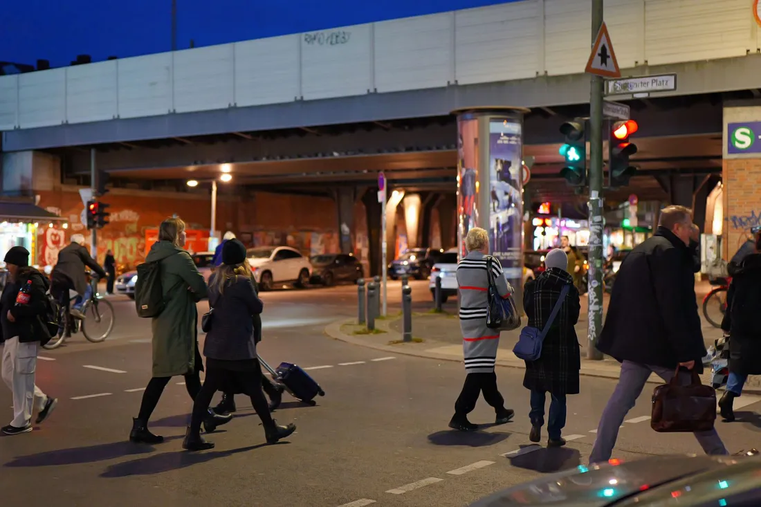 Fußgänger an einer Berliner Kreuzung unter einem S-Bahn-Viadukt am Abend