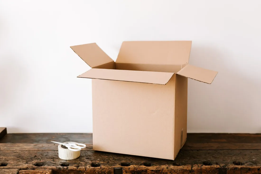 Umzugsmaterial mit Kartons, Packpapier, Folie und Klebeband auf einem Tisch